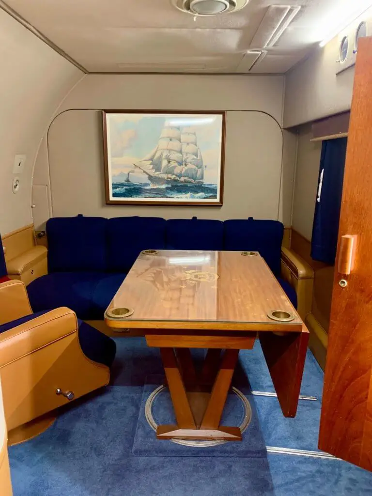 Office area with blue sofa and wooden table inside a presidential plane