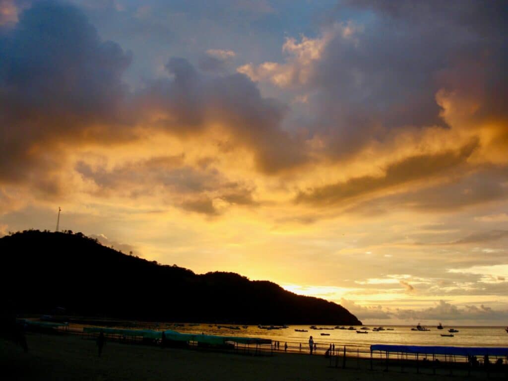 Blue-orange sunset over a silhouetted headland and ocean