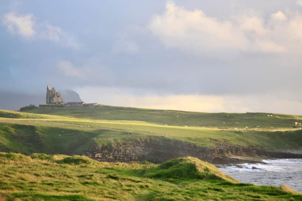 Green sea cliffs, turbulent water, and Classiebawn Castle