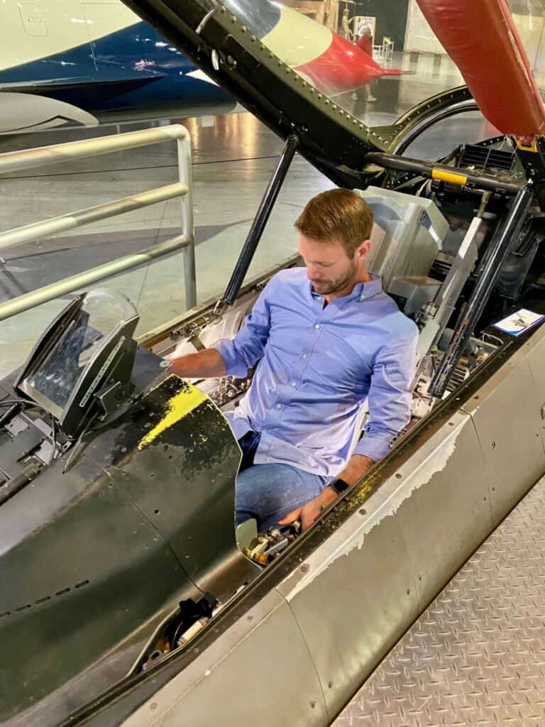 M sitting in a fighter jet cockpit